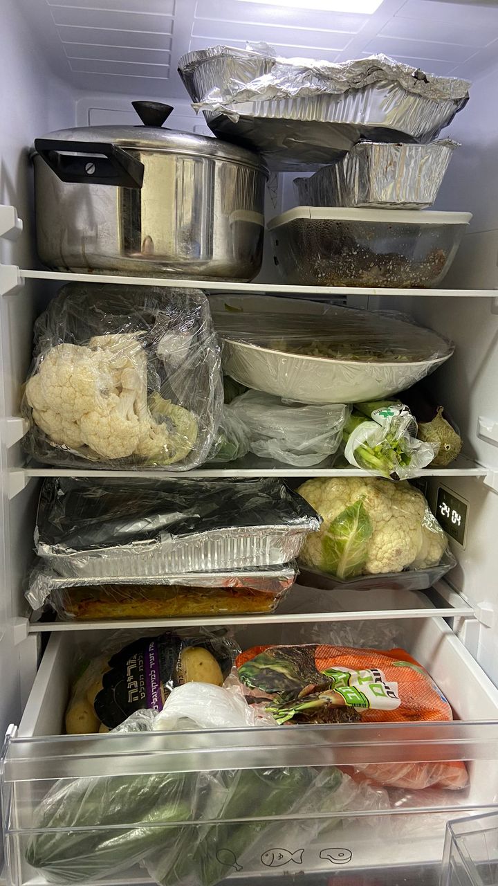 A large pot taking up the top shelf of a fridge
